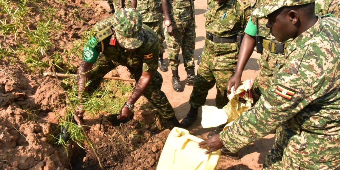 Col-Hyeroba-planting-a-tree-outside-the-his-office-compound-as-other-officers-look-on